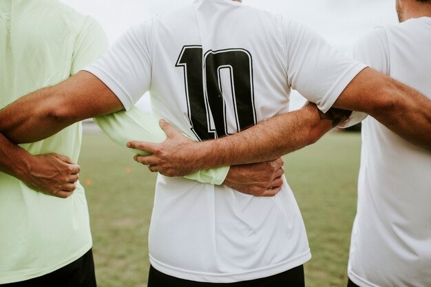 Three soccer players standing with arms around each other, showing the back of a white jersey with the number 10.