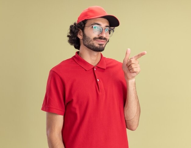 A delivery man wearing a red cap and polo shirt, representing custom work polo shirts, pointing to the side.